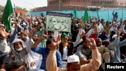 A supporter of the Tehreek-e-Labaik Pakistan, an Islamist political party, holds a sign, which reads in Urdu, "remove Zahid Hamid" during a sit-in protest along a main road in Karachi, Nov. 27, 2017. 