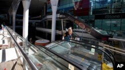 An employee walks off an escalator at a closed mall in Caracas, Venezuela, Feb. 10, 2016.