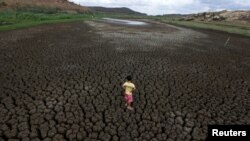 FILE - Natan Cabral, 5, stands on the cracked, dry ground of the Boqueirao reservoir in the Metropolitan Region of Campina Grande, Paraiba state, Brazil, Feb. 13, 2017.