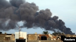 La fumée monte d’une usine après une frappe des forces loyales au maréchal Khalifa Haftar à Benghazi, Libye, 22 octobre 2014.