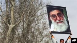 A pro-government Iranian holds a poster of supreme leader Ayatollah Ali Khamenei during the funeral ceremony of Sane Jaleh, a student who was killed during Monday's clashes, in Tehran, Iran, February 16, 2011