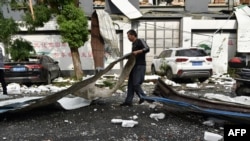 A man cleans up damage after a tornado hit the city of Suzhou in China's eastern Jiangsu province on May 15, 2021.