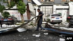 A man cleans up damage after a tornado hit the city of Suzhou in China's eastern Jiangsu province province on May 15, 2021. (Photo by STR / AFP) / China OUT