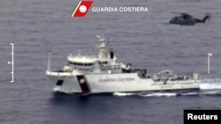 An Italian coast guard vessel is seen with an helicopter during the search and rescue operation underway after a boat carrying migrants capsized overnight, with up to 700 feared dead, in this still image taken from video, April 19, 2015.