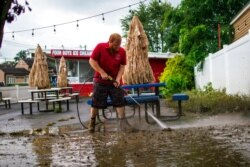 A worker cleans the outside area of Four Boys Ice Cream store during the passing of Tropical Storm Henri in Jamesburg, N.J., Aug. 23, 2021.