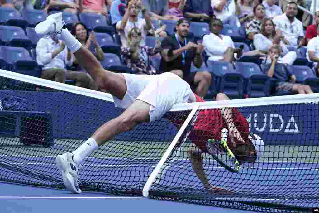 Oscar Otte of Germany, falls over the net during his match against Matteo Berrettini of Italy in the fourth round of the U.S. Open tennis championships, Sept. 6, 2021, in New York.