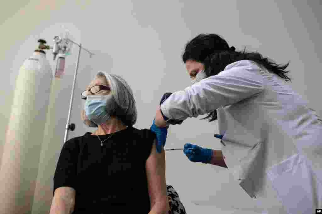 یک زن اولین دُز واکسن کرونای فایزر ساخت آمریکا را در یک مرکز واکسیناسیون در نزدیکی آتن در یونان، دریافت می‌کند.