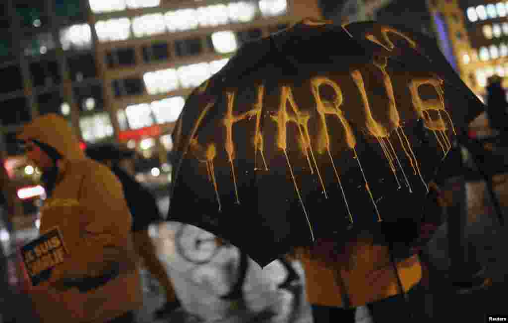 A person holds an umbrella as others brave heavy rain holding placards reading "I am Charlie," to pay tribute to victims of the attack on the Paris office of Charlie Hebdo, during a vigil in Frankfurt, Jan. 8, 2015,