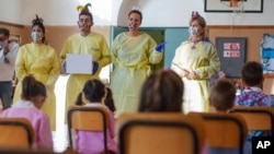 Medical personnel talk to children as they prepare them to receive non-invasive Covid 19 tests with chewing gum at the G.B. Grassi school, in Fiumicino, near Rome, Oct. 6, 2020.