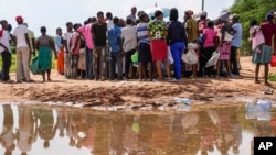 Residents gather for a planned distribution of food, after El Niño rains damaged their houses in Bangale town in Tana River county, Kenya, Sunday, Nov. 26, 2023.