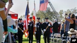 A U.S. flag hangs from the ladder of a firetruck as a color guard made up of Santa Rosa firefighters presents the colors to start a Day of Remembrance memorial for victims of California wildfires, in Santa Rosa, Oct. 28, 2017.