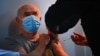 A man receives a dose of Covid-19 vaccine at a vaccination truck parked outside his residential building in the Parisian suburban city of Stains on March 2, 2021. (Photo by Anne-Christine POUJOULAT / AFP)