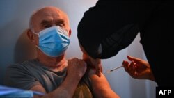 A man receives a dose of Covid-19 vaccine at a vaccination truck parked outside his residential building in the Parisian suburban city of Stains on March 2, 2021. (Photo by Anne-Christine POUJOULAT / AFP)