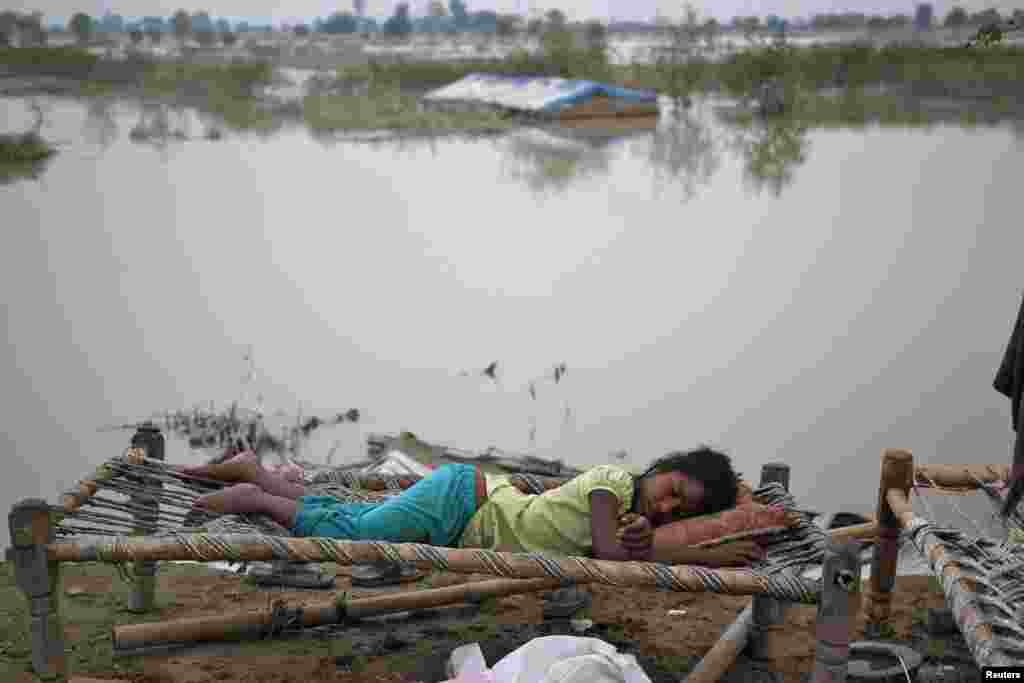 Một em gái ngủ bên ngoài căn lều tạm bợ tại một khu trại bên đường sau khi sông Yamuna dâng nước ví những trận mưa to ở New Dehli.