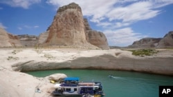 Sebuah rumah kapal bersandar di teluk kecil yang menjadi bagian dari Danau Powell di Page, Arizona, pada 30 Juli 2021. Pada musim panas 2021, level ketinggian air di danau tersebut mencapai titik terendah dalam sejarah akibat kekeringan yang melanda. (Foto: AP/Rick Bowmer)