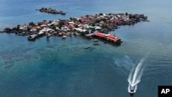 Funcionarios de protección civil trasladan las pertenencias de los residentes en un barco al continente desde la isla Gardi Sugdub, arriba, frente a la costa caribeña de Panamá, el miércoles 5 de junio de 2024