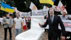 FILE - Anti-corruption activists, wearing masks of government officials, hold a rally outside parliament in Kyiv, Ukraine, June 15, 2015.