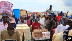 FILE - People carry items into Haiti from the Dominican Republic in Malpasse, Haiti, April 1, 2010.