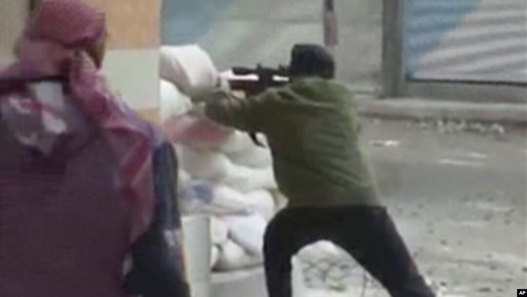 A rebel fires a weapon around a corner at Syrian government forces in Damascus, Syria, December 7, 2012.