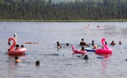 Children play with inflatable flamingos and other creatures at Goose Lake, July 5, 2019, in Anchorage, Alaska.