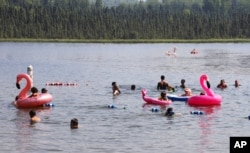 Children play with inflatable flamingos and other creatures at Goose Lake, July 5, 2019, in Anchorage, Alaska.