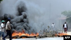 Un habitant de Lusaka passe devant des pneus en feu, Zambie, le 12 janvier 2018