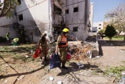 Soldiers help to carry residents' personal belongings out of a damaged building following a rocket attack from Gaza, in Ashdod, Israel, May 17, 2021.
