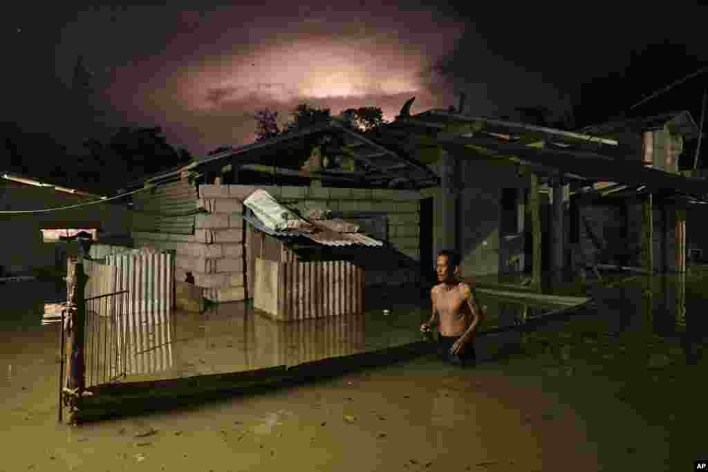 A resident wades through a flooded street caused by heavy rains from typhoon Toraji in Ilagan City, Isabela province, northern Philippines.