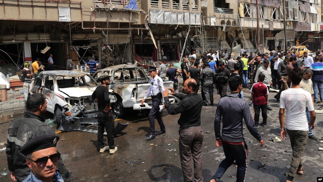Pasukan keamanan dan warga Irak memeriksa lokasi serangan bom mobil di distrik Karrada, Baghdad, Sabtu (9/5).