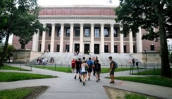 Para mahasiswa berjalan di dekat Perpustakaan Widener di Universitas Harvard di Cambridge, Massachusetts, 13 Agustus 2019. (Foto: AP)