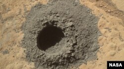 NASA's Mars rover, Curiosity, completed a shallow "mini drill" activity as part of an evaluatiion of a rock target called "Windjana" for possible full-depth drilling to collect powdered sample material from the rock's interior, April 29, 2014. 