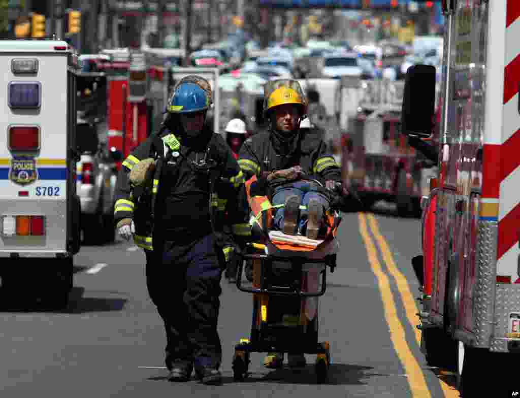 Rescue personnel evacuate an injured person from the scene of a building collapse in Philadelphia, Pennsylvania, June 5, 2013. 