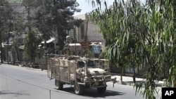 A NATO military vehicle crosses the empty street after gunmen launched an attack on the compound of the governor of Kandahar province in Kandahar, south of Kabul, Afghanistan, May 7, 2011