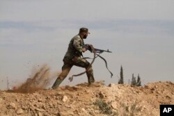 FILE - A Shiite fighter clashes with members of the Free Syrian Army rebel group in the town of Hatita, in the countryside of Damascus, Syria.