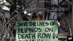 A member of Migrante International, a Filipino migrant organization, displays a placard demanding legal assistance for her relatives during a protest outside the presidential palace in Manila, February 21, 2011.