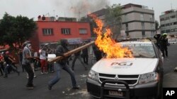 Para pemrotes membakar mobil polisi saat berunjuk rasa di Mexico City, Kamis (20/11).