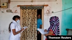 Health workers collect personal data from a man during a door-to-door survey for the first shot of COVID-19 vaccine for people over 50 years of age and those with comorbidities, in a village near Ahmedabad, India, Dec. 14, 2020.