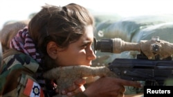 An Iranian-Kurdish female fighter aims with her weapon during a battle with Islamic State militants in Bashiqa, near Mosul, Iraq, Nov. 3, 2016.