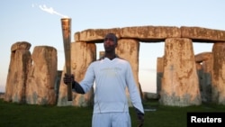 Former U.S. Olympic athlete Michael Johnson holds the Olympic Torch at Stonehenge, a World Heritage site, in Salisbury, southern England, July 12, 2012.