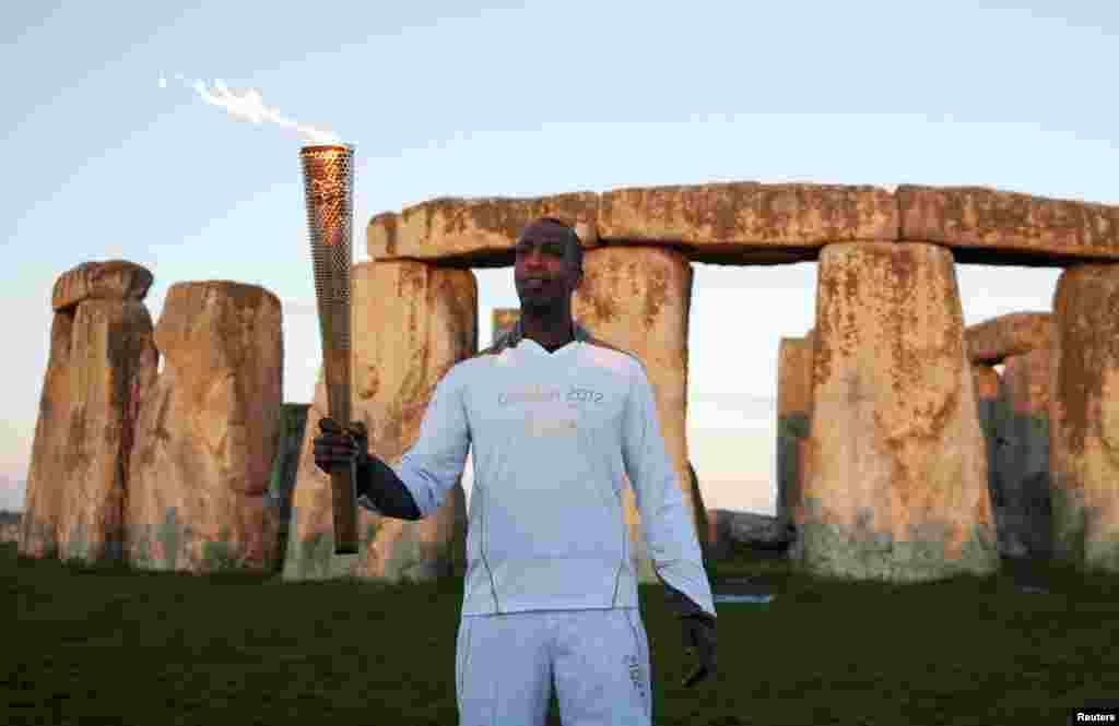 Mantan atlet Olimpiade dari AS Michael Johnson memegang obor Olimpiade di tempat bersejarah Stonehenge, selatan Inggris (12/7).