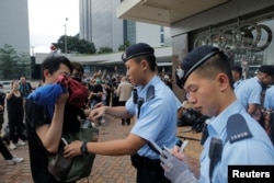 A police officer checks the bag of a pedestrian following a day of violence over an extradition bill that would allow people to be sent to mainland China for trial, in Hong Kong, June 13, 2019.