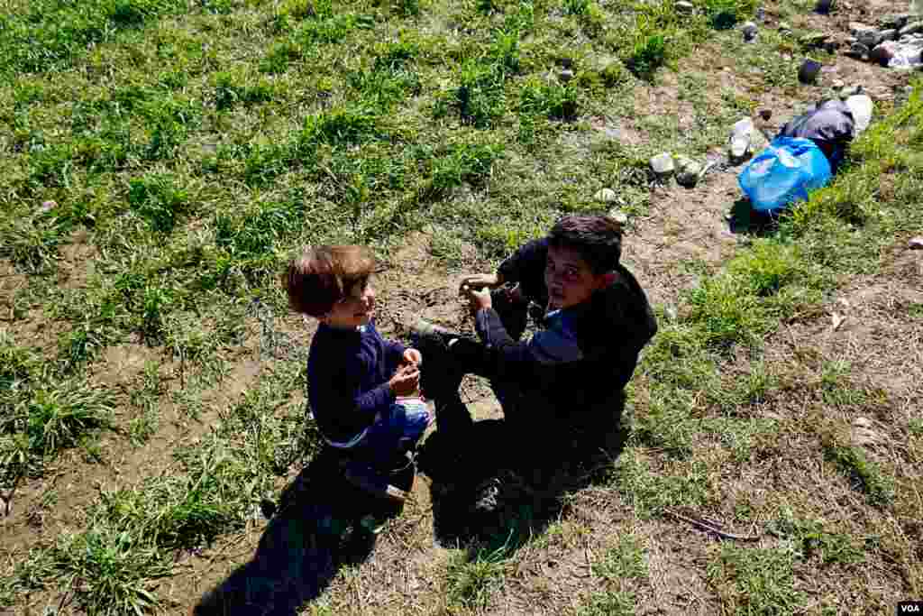 Children play on grass at Idomeni refugee camp on the Greece-Macedonia border, March 8, 2016. (Jamie Dettmer for VOA)