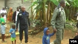 Police officers lead away children after the search of a suspect's home in Kiossi, Cameroon, March 3, 2018. (M. Kindzeka/VOA)