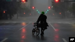 Ron Rook, who said he was looking for people in need of help or debris to clear, walks through windy and rainy conditions on a deserted street in downtown Tampa, Fla., during the approach of Hurricane Milton, Oct. 9, 2024.