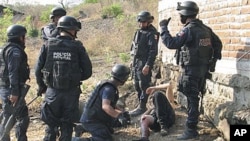 Federal police officers stand over an injured man, allegedly belonging to the La Familia Michoacana drug cartel, after a gun battle was held a day earlier in Jilotlan, Mexico, May 28, 2011 (file photo)