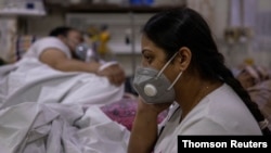 Manika Goel sits next to her husband, who has the coronavirus disease (COVID-19), inside the emergency ward at Holy Family hospital in New Delhi, India, April 29, 2021.