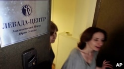 FILE - Levada polling agency employees leave their Moscow office, May 20, 2013, when the agency was targeted during a Kremlin crackdown on civil society. Now, Russia’s government has labeled it a ‘foreign agent.’