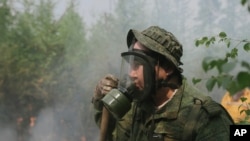 Maxim Yefremov, member of volunteers crew adjusts his gas mask as he mops up spot fires at Gorny Ulus area west of Yakutsk, Russia, July 22, 2021.