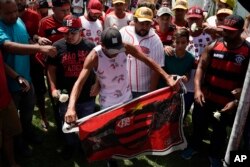A fan holds a Flamengo flag as he and other fans pay homage to the fire victims at the entrance of the Flamengo soccer club training complex in Rio de Janeiro, Brazil, Feb. 8, 2019.