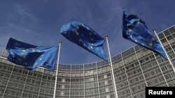 FILE - European Union flags flutter outside the European Commission headquarters in Brussels, Belgium, March 24, 2021. 